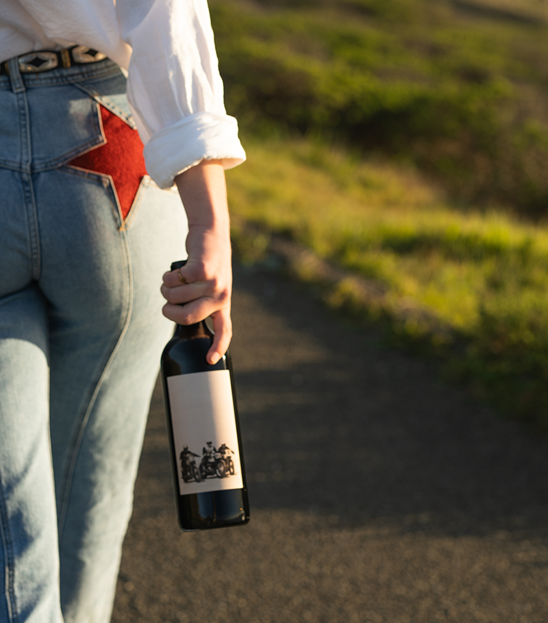 Hannah holding a bottle of Soul Fuel next to her jeans with red star pockets.