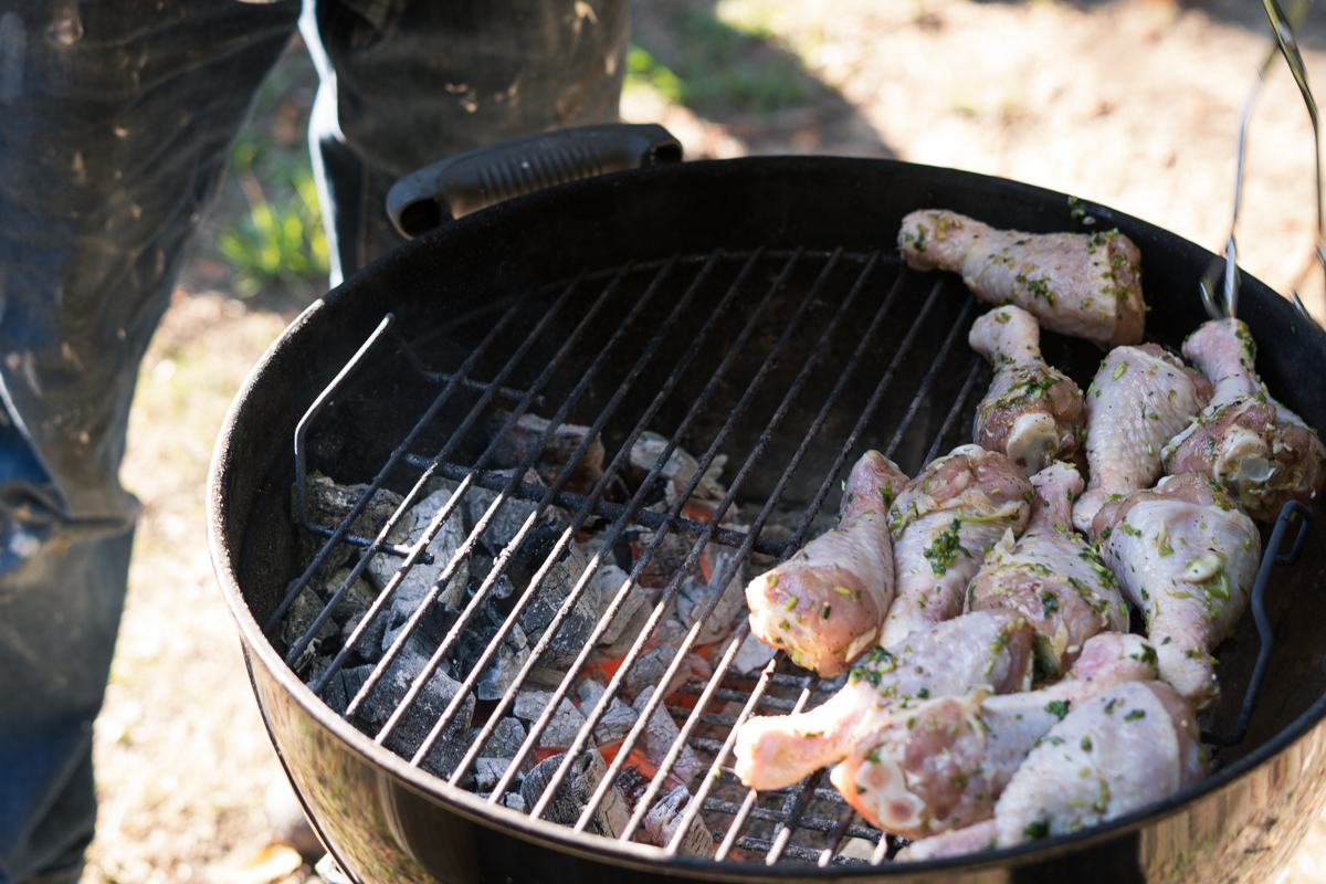 Chicken being placed on a charcoal grill