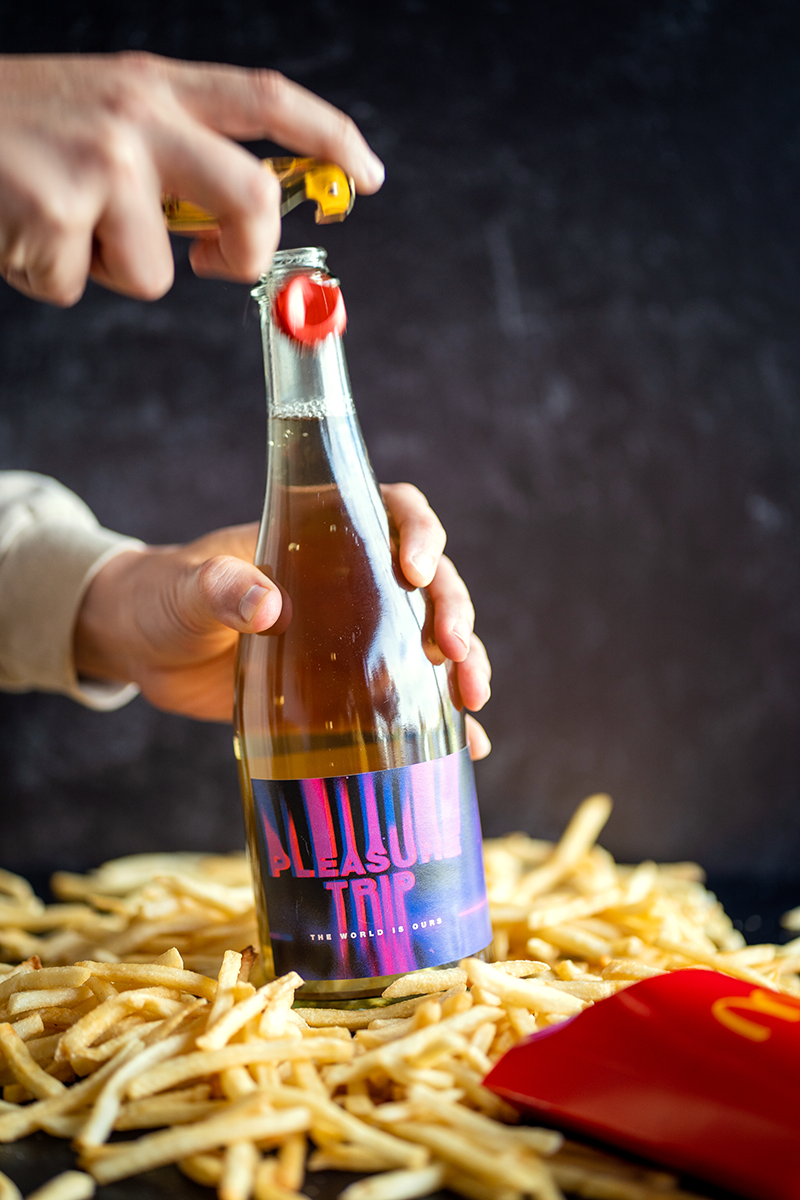 A bottle of Pleasure Trip surrounded by Mcdonalds french fries.
