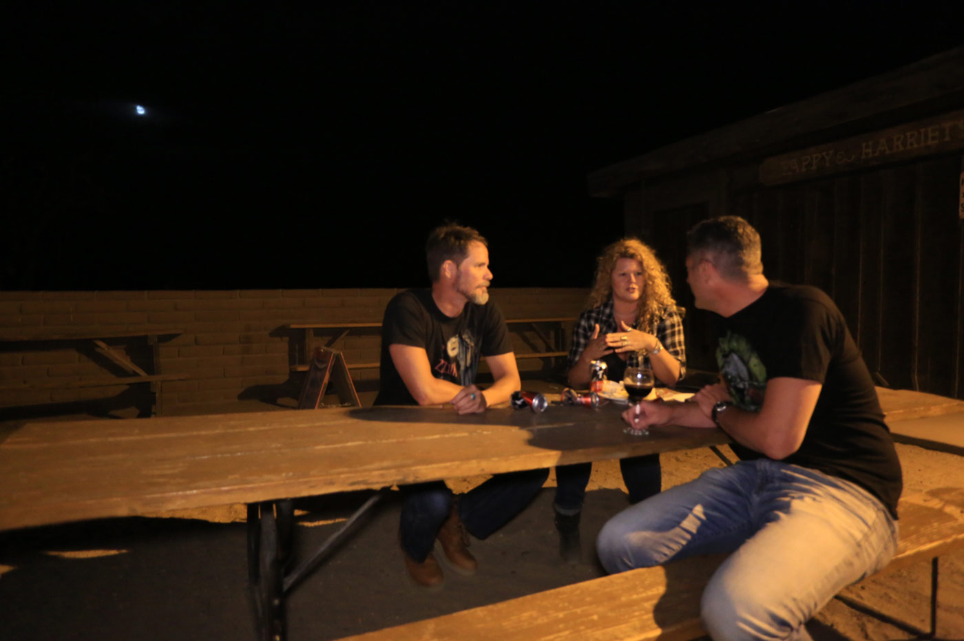 Three people talking on picnic table